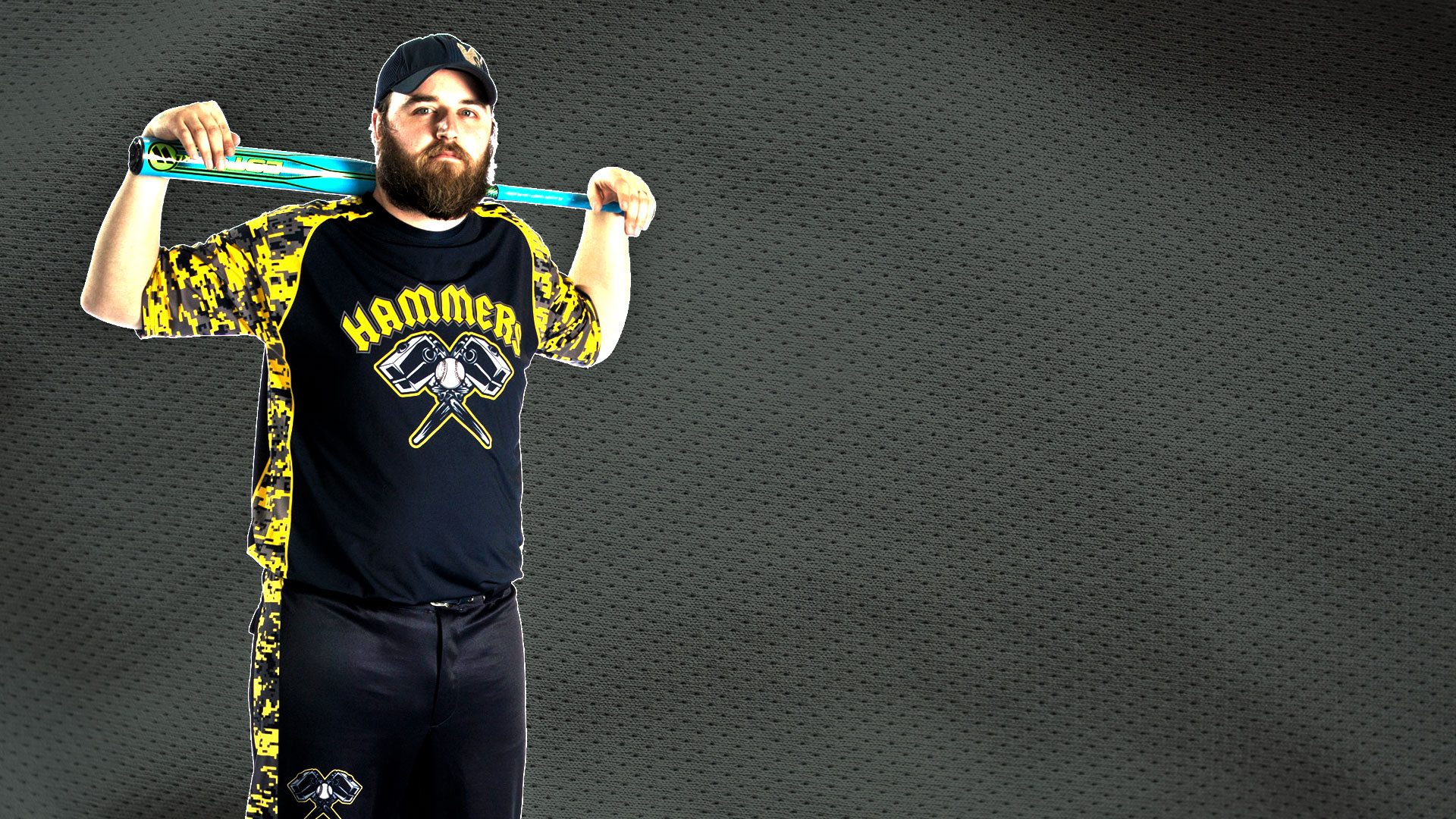 Man holding bat in custom designed softball jersey and sofball pants.